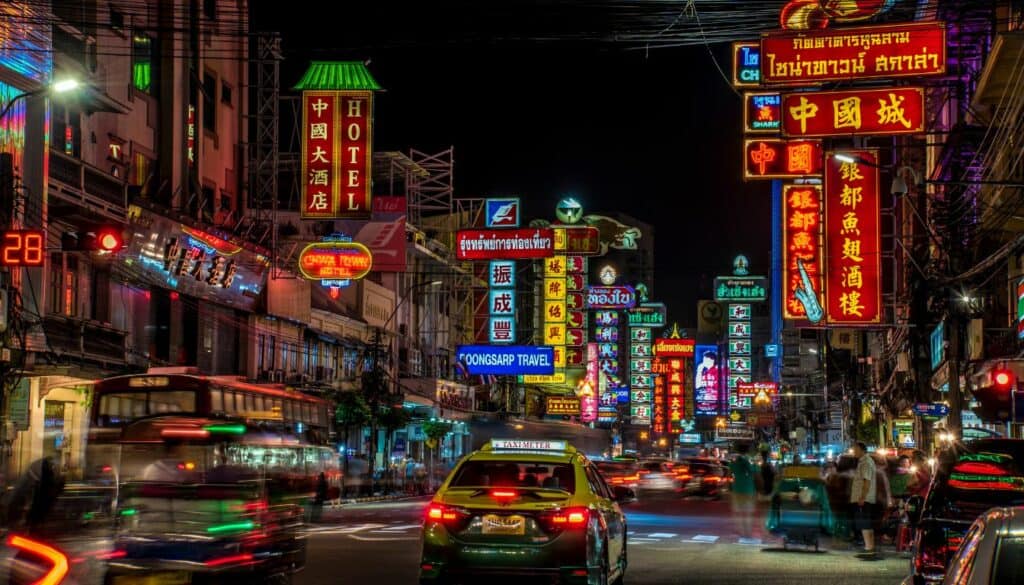 Bangkok by night. In the image there are a lot of neon lights and traffic. Also Bangkok taxis