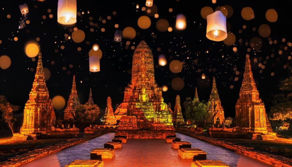 the image is of the Loy Krathong festival and shows different temples with orange colors and floathing yi pengs in the air, which are floating lanterns.